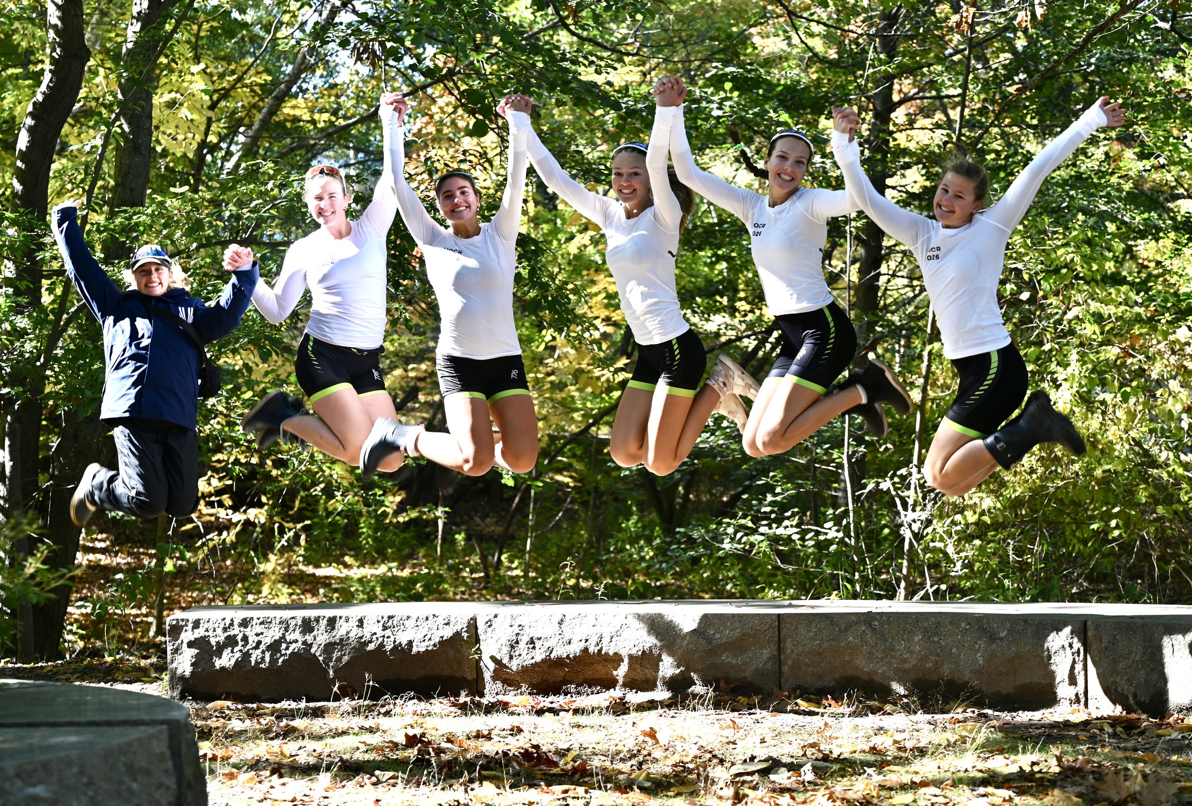 Connecticut Boat Club teammates jumping together at the Head of the Charles