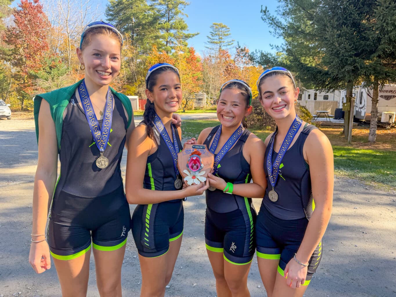 Four CBC rowers with their medals, holding their Head of the Fish trophy